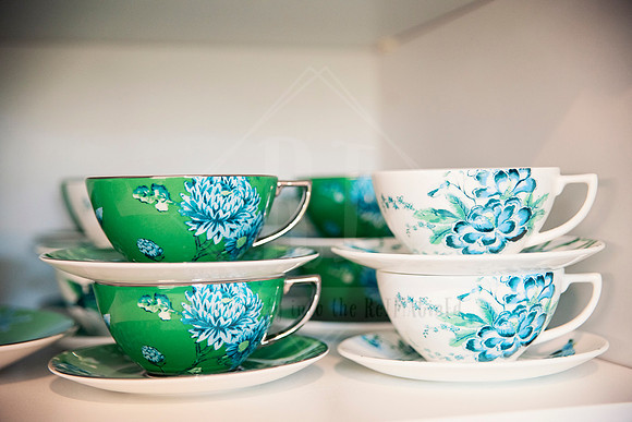Stacked green and aqua patterned tea cups and saucers in kitchen nook.