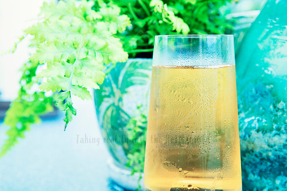 Golden drink in a frosted glass with trailing greenery behind it.