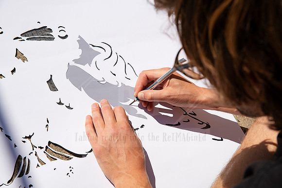 Hands using a blade to cut out intricate stencil design, detailed close-up for Artwalk behind-the-scenes content.