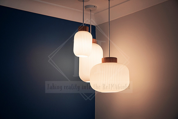 Three hanging pendant lights with ribbed glass shades against navy feature wall.
