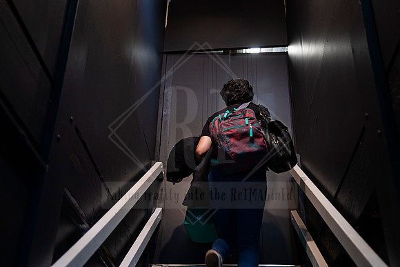 Back view of visitor walking upstairs into Sunset Framing & Gallery through a dramatic black entryway.