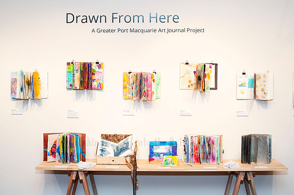 Wide view of community art exhibition with vibrant journals on display, photographed for creative project documentation.