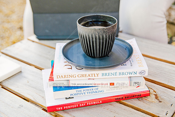 Coffee mug resting on top of stacked books including “Daring Greatly” by Brené Brown, styled for mindful business branding.