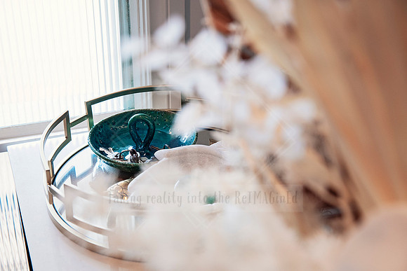 Decorative tray styled with teal glassware and soft dried florals in a luxe setting.