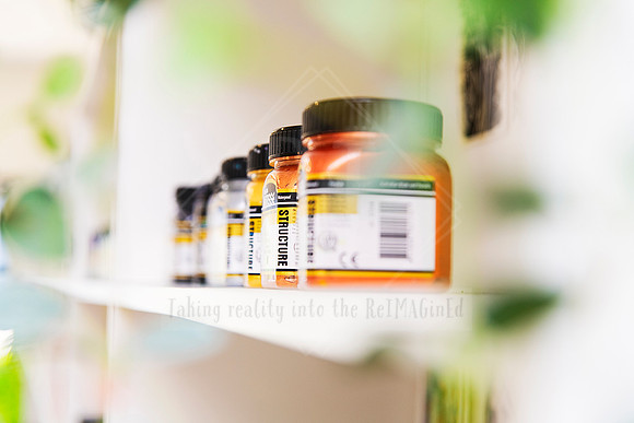 Shelf of golden acrylic paints with soft focus background.